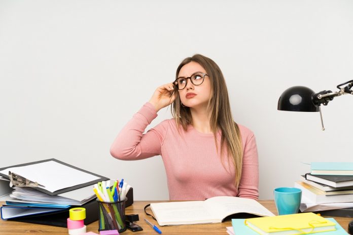 Teenager student girl in her room having doubts and with confuse face expression